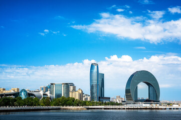 Daytime view of Baku’s modern skyline along the Caspian waterfront with glass towers and contemporary architecture under a blue sky.