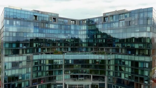 Architectural 4K Ultra HD tilt up video over the large modern glass facade building of a U shape international headquarter designed to house multiple companies and offices