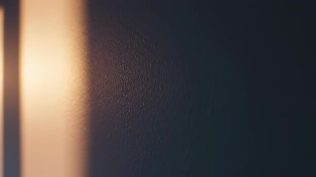 Serene Sunlight on the Wall: A warm shaft of sunlight gracefully illuminates a textured wall. The play of light and shadow, revealing the subtle beauty of the surface. Capturing calm mood.