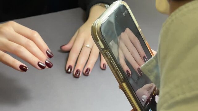 Manicurist filming manicure work with smartphone for social media promotion in nail salon - Powered by Adobe