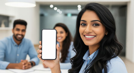 A cheerful young Indian professional holds up a smartphone with a blank white screen