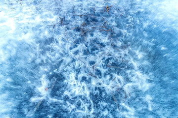 Amazing ice structure with cracks and air bubbles. Frozen grass in ice. Winter pattern.