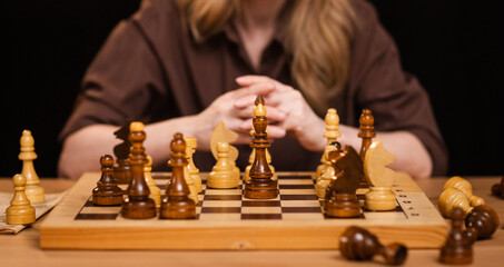 pretty girl with blond hair plays chess on a dark background