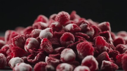 Close-up of frozen raspberries cascading onto a bed of berries, creating a vibrant texture