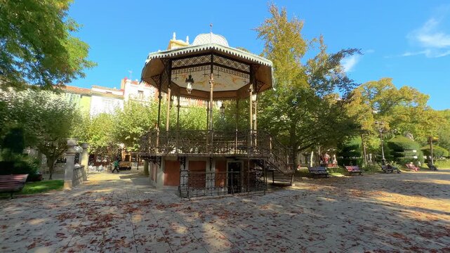 Historic iron bandstand at Paseo del Espolon in Burgos, Spain, surrounded by trees and autumn leaves. A peaceful urban scene showcasing traditional architecture and cultural charm. 