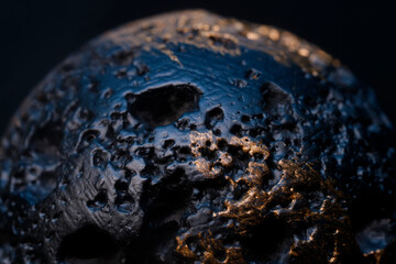 Macro view of black porous asteroid surface with gold minerals. Concept of dangerous meteorite, dead planet crater, or unknown alien rock object in deep dark space. Photo