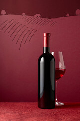 Fototapeta premium Bottle and glass of red wine on a red background.
