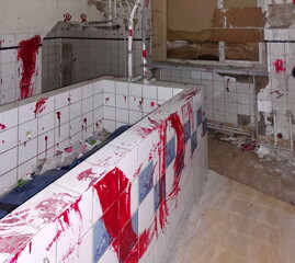 Red-stained tiled bath in an abandoned interior with visible decay and peeling tiles