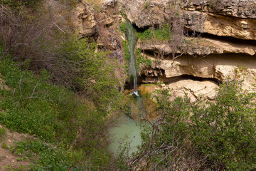 A small waterfall with a lake in the mountains.