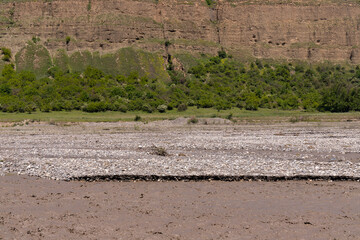 A muddy river in a canyon in the mountains.