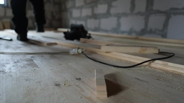 Wood floor installation, worker picking up hand saw before cutting lumber. DIY construction close-up