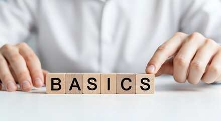 Person arranging wooden blocks spelling the word basics on a white table surface, isolated on white background