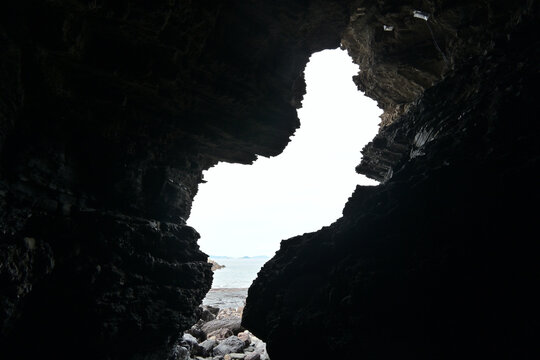 A view of the exit from the inside of a naturally formed cave somewhere on the rocky cliff - Powered by Adobe