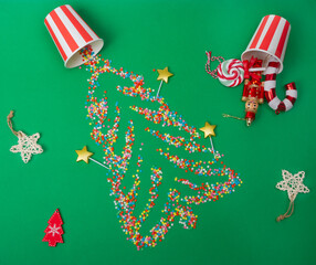 Christmas background. Sugar stars shaped like a Christmas tree are scattered across a green background, along with Christmas tree ornaments