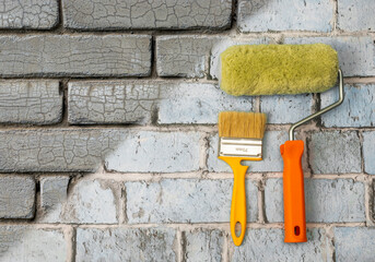 Creative background for renovation. Roller and brush against a gray brick background. Renovation tools