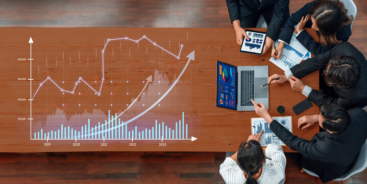 A dynamic business team engaged in data analysis and strategy planning, utilizing digital tools like laptops and tablets to discuss trends and performance metrics in a modern office. Scalp - Powered by Adobe