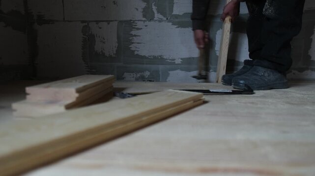 Wood floor installation tapping board into place in real home construction