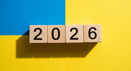 Anticipating 2026 Wooden blocks spell out the future year, resting on a background of national colors, symbolizing hope, progress, and a strategic outlook for the times ahead