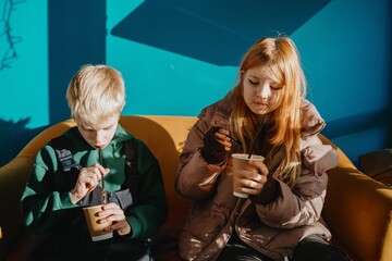 A 12-year-old teenage girl enjoys breakfast in a cozy cafe with fast food. Authentic moment of teen independence, urban lifestyle and casual dining