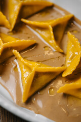 Close-up of ravioli pasta in rich sauce with olive oil, Italian restaurant dish.