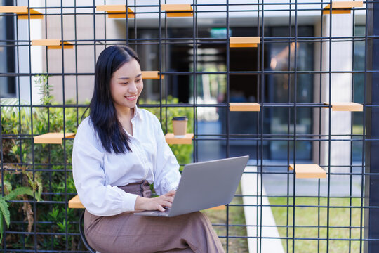Young woman remotely working on laptop in modern outdoor cafe