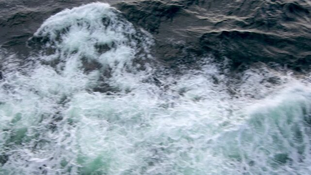 Dynamic northern rough ocean waves with choppy water and white sea foam captured from a ship, showcasing powerful dark sea motion. Perfect for travel, nature, and dramatic maritime video backgrounds