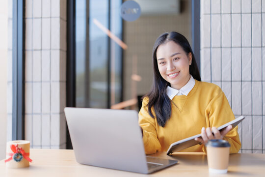 Asian woman smiling using laptop and tablet for remote work - Powered by Adobe