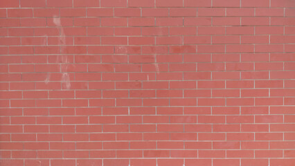 A brick wall with a red color. The wall is made of bricks and has a rough texture. Historic wall backdrop of red bricks