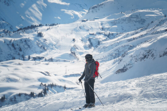 A male skier in the famous and snow secure Ski Arlberg near Lech and Z&uuml;rs enjoing the sunlit piste below Kriegerhorn, dazzling powder and blue sky radiate alpine freedom, ideal for winter sport ads.