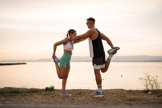 Couple stretching together outdoors by the sea at sunset - Powered by Adobe