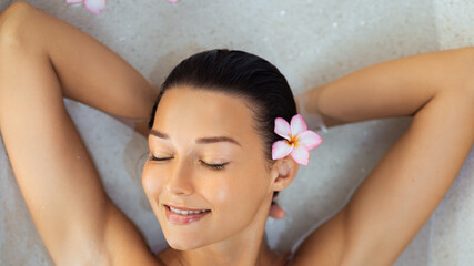 Beautiful Young Woman With Flower In Hair Relaxing In Luxury Spa Bath