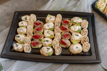 Delicious assortment of bite-sized appetizers on a black tray at a gathering