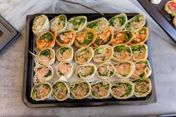 Colorful assortment of freshly made wraps arranged on a tray at a casual gathering event during the afternoon
