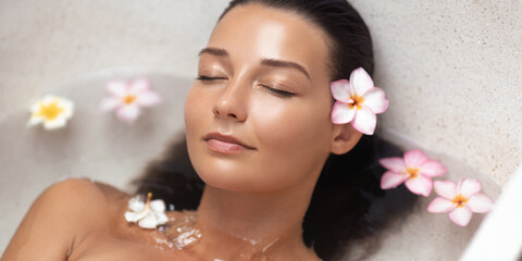 Peaceful Woman Relaxing In Spa Bath With Floating Tropical Flowers 