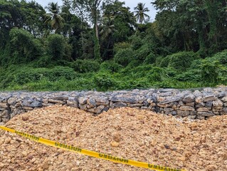 The construction of a gabion wall or gabion basket in Trinidad and Tobago. This is a type of retaining wall used for erosion control and riverbank reinforcement. 