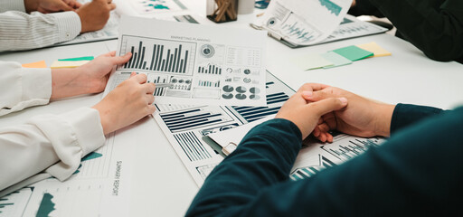 A diverse team collaborates in a modern office setting, analyzing charts and graphs during a business meeting. The atmosphere promotes teamwork and strategic planning. SACTR