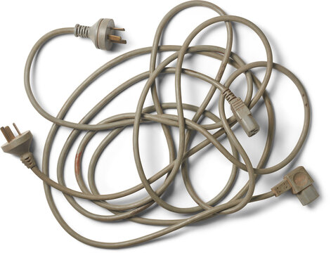 tangled heap of three-pronged electrical power cords, muted gray cables with plugs and connectors isolated white background, top view of dirty electronic waste