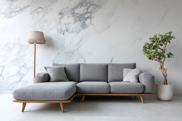 Modern grey sectional sofa with lamp and plant against marble wall.