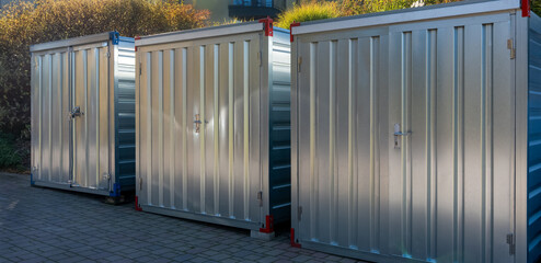 Row of metal storage containers outdoors in sunlight