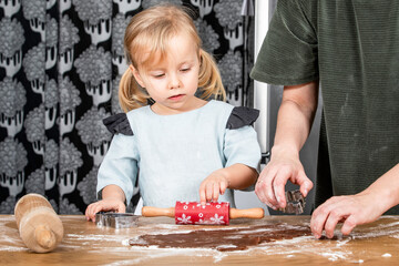 Child and Adult Preparing Gingerbread Dough with Cookie Cutters at Kitchen Table
