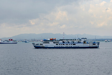 Passenger Ferry on Calm Sea with Coastal City and Mountains