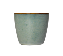 ceramic cup with a smooth tapered form and muted turquoise glaze stands isolated on a bright