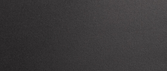 Wide horizontal close-up of dark textured paper with fine grain and a subtle matte finish, forming a