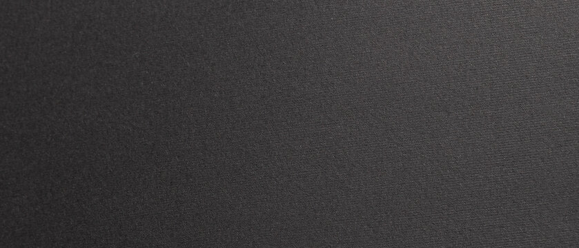 Wide horizontal close-up of dark textured paper with fine grain and a subtle matte finish, forming a