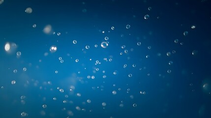 Numerous small bubbles and water droplets suspended in a deep blue glowing liquid with soft light effects