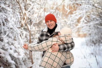 Father and daughter playing and enjoying the snow in a winter forest. Concept of family joy, warm emotions, childlike happiness, and fun winter activities outdoors.
