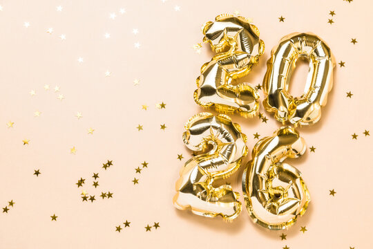 New year 2026 celebration card mockup. Gold foil helium balloon number 2026, party decoration, gold confetti stars on beige background. Copy space, flat lay, merry christmas, happy holidays concept.