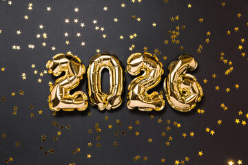 New year 2026 balloon celebration card. Gold foil helium balloons number 2026, party decoration, golden confetti stars on dark background. Flat lay, merry christmas banner, happy holidays concept.