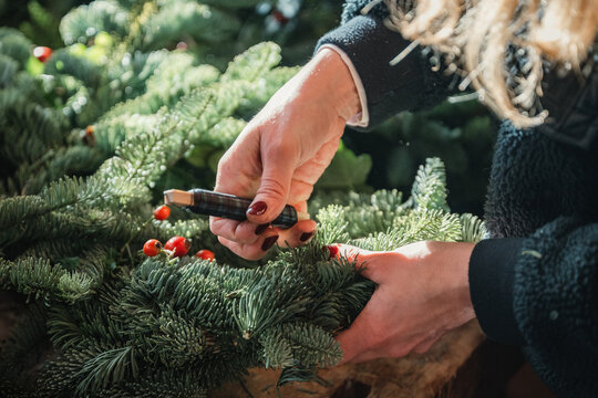 H&auml;nde gestalten weihnachtlichen Kranz aus Tannenzweigen