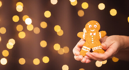 gingerbread man in female hands on christmas background among new year lights